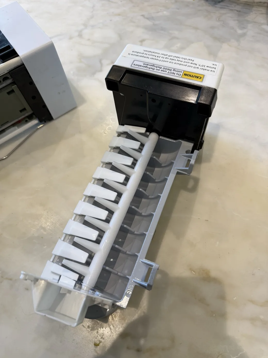 A removed refrigerator ice-maker assembly on a work surface